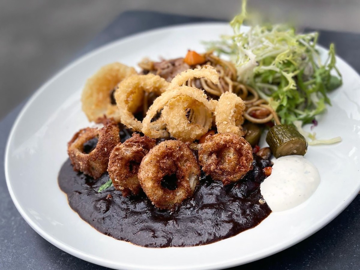 A plate of Japanese curry with fried onions and greens from Delo Curo.