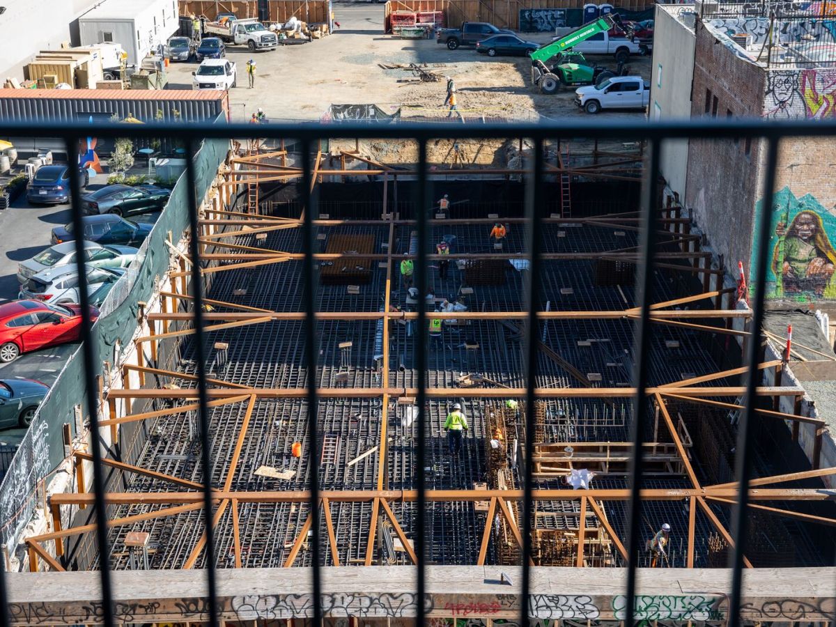 A birds-eye-view of an urban construction site, from the balcony of a tall building.