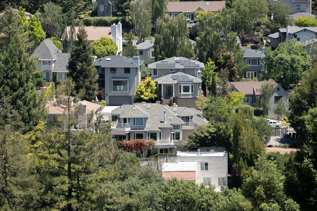 Large houses on a hillside surrounded by dense vegetation.